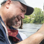 Photo of high school student Quienten Anger measuring nitrate value in the Chippewa River with Professor J. Brian Mahoney. Willow Anderson in the background.