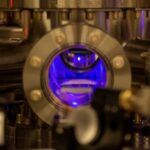 Photo of one of the first steps in creating the optical atomic clocks used in this study, which is to cool strontium atoms to near absolute zero in a vacuum chamber, which makes them appear as a glowing blue ball floating in the chamber. IMAGE PROVIDED BY SHIMON KOLKOWITZ