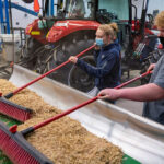 Photo of students Rames Frisch, in tractor, Alex Pierson and Kyle Leis conducting research to determine how to improve a 1960s combine’s performance.