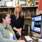 Photo of Krista Lisdahl (standing), professor of psychology, and graduate student Ashley Stinson looking at brain scans of adolescents participating in the ABCD Study, the largest long-term study of brain development and child health in the United States. (UWM Photo/Troye Fox)