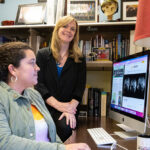 Photo of Krista Lisdahl (standing), professor of psychology, and graduate student Ashley Stinson looking at brain scans of adolescents participating in the ABCD Study, the largest long-term study of brain development and child health in the United States. (UWM Photo/Troye Fox)