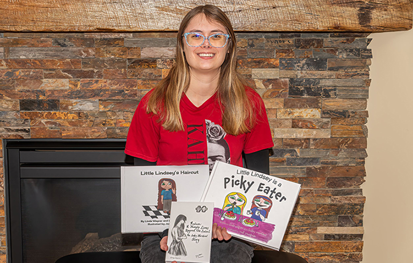 Photo of University of Wisconsin-River Falls alum Lindsey Moreland holding three books she has authored