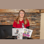 University of Wisconsin-River Falls alum Lindsey Moreland holding three bokks she authored about living with autism