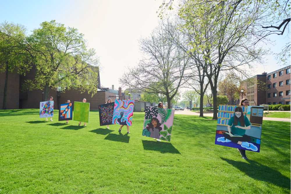 Photo of UW-La Crosse art students parading their work across campus from the Center for the Arts to Murphy Library. The students participated in an initiative of Murphy Library staff Amber Leibundgut-Peterson and Marc Manke, both eager to promote the work of student artists and create a more vibrant, creative learning environment in the library.