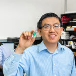 Photo of Yi Hu holding a prototype of the hearing device he developed for the over-the-counter hearing device market. The FDA is expected to issue guidelines for approval of OTC devices soon. (UWM Photo/Elora Hennessey)