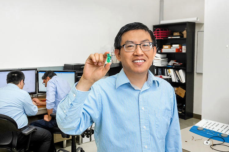 Photo of Yi Hu holding a prototype of the hearing device he developed for the over-the-counter hearing device market. The FDA is expected to issue guidelines for approval of OTC devices soon. (UWM Photo/Elora Hennessey)