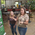 Photo of UW-Eau Claire public history graduate students Jordan Stish (left) and Alexi Linder discussing the exhibit they helped create in the Irvine Park Welcome Center in Chippewa Falls. (Photo by Shane Opatz)