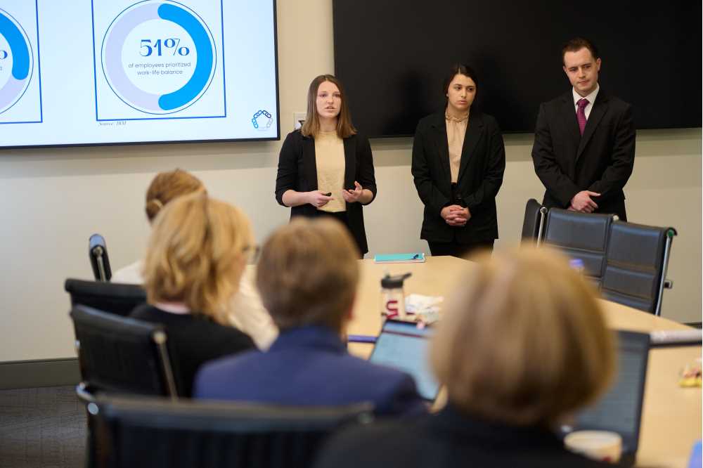 Photo of (from left): UWL students Alissa St. Louis, Teagan Hammen and Jack Murphy sharing their research findings with representatives from Kwik Trip. Recommendations included increased benefits and resources, such as employer-sponsored childcare, and more flexible scheduling policies.