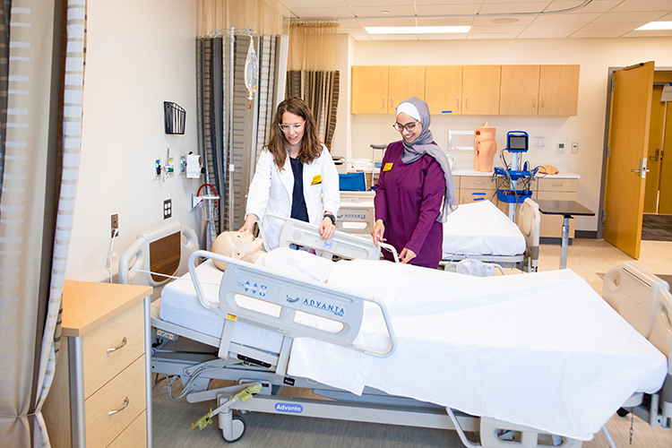 Photo of Melissa Melcher (left), clinical assistant professor, and Bayan Alqam, teaching assistant and PhD nursing student, checking a manikin in the Clinical Skills Lab at the new UWM James and Yvonne Ziemer Clinical Simulation Center. (UWM Photo/Elora Hennessey)