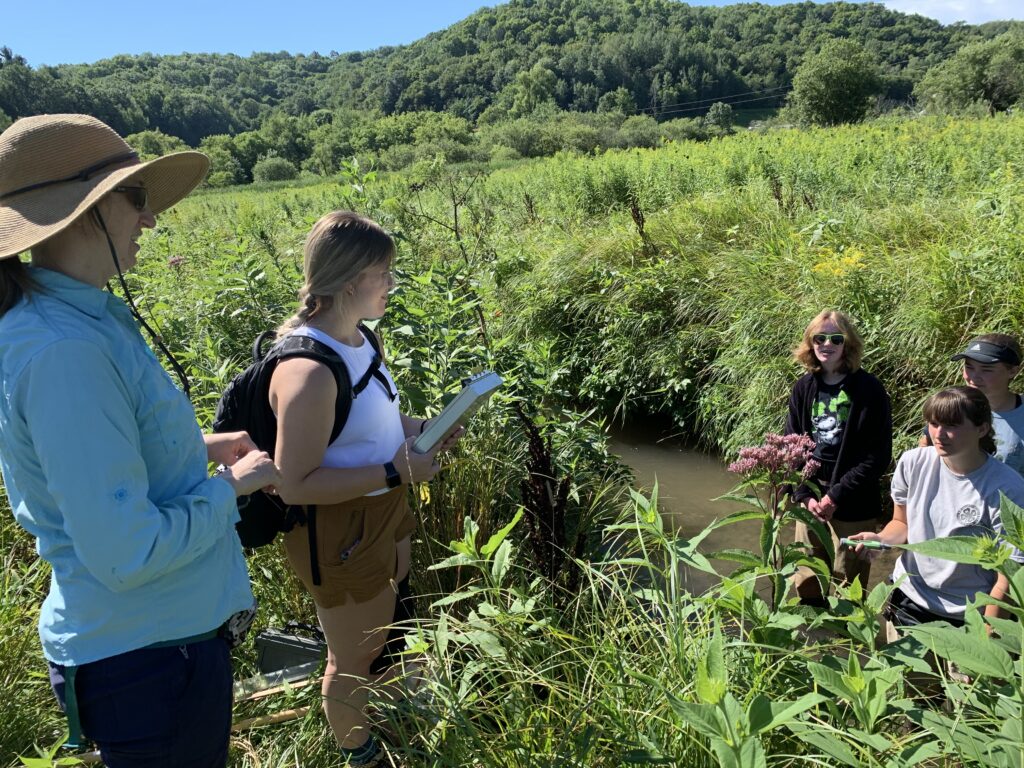 Photo of UW-Stout Assistant Professor Nicole Hayes, left, guiding three high school students as they conduct tests on Gilbert Creek west of Menomonie. / UW-Stout