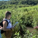 Photo of UW-Stout Assistant Professor Nicole Hayes, left, guiding three high school students as they conduct tests on Gilbert Creek west of Menomonie. / UW-Stout