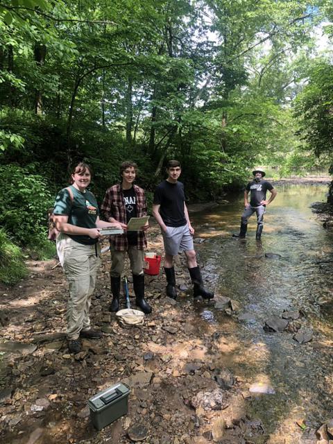 Photo of (from left) UW-Stout students Britney Serafina, Kal Breeden and Dylan Kostuch and Associate Professor Keith Gilland conducting research in a stream this summer. / UW-Stout