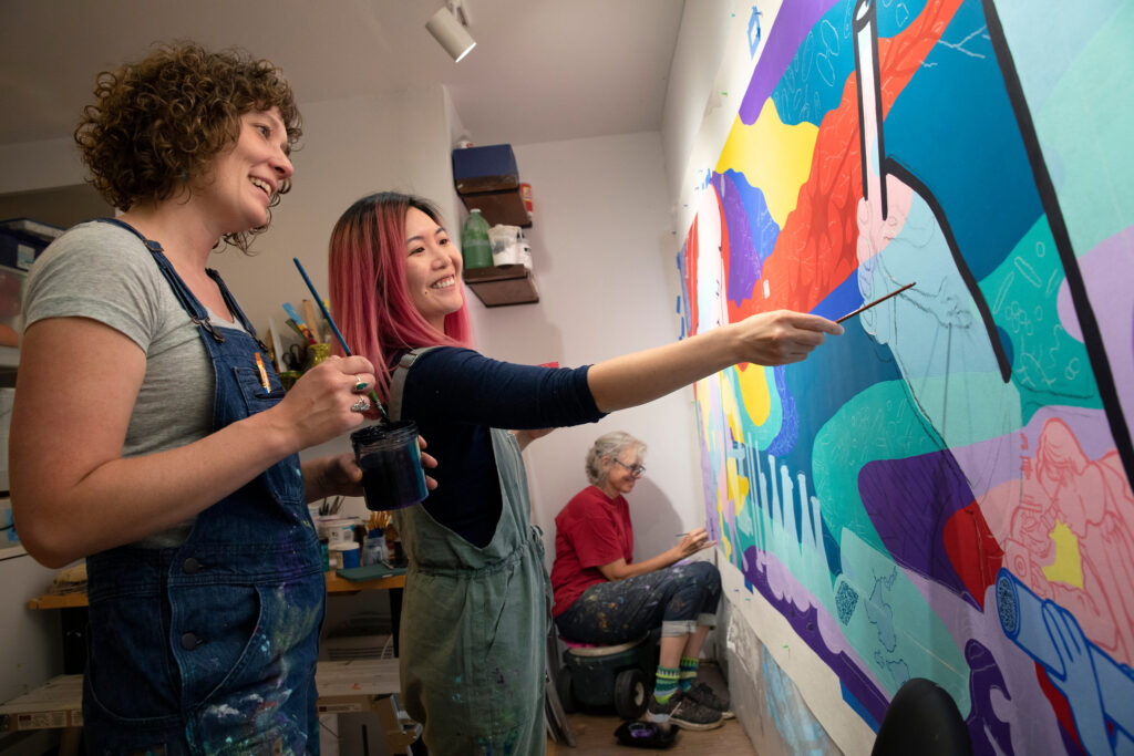 Photo of (from left) artists Amy Zaremba, Sharon Tang, and Alicia Rheal working on a science-oriented mural at Zaremba’s home studio on the east side of Madison, Wis. MICHAEL P. KING