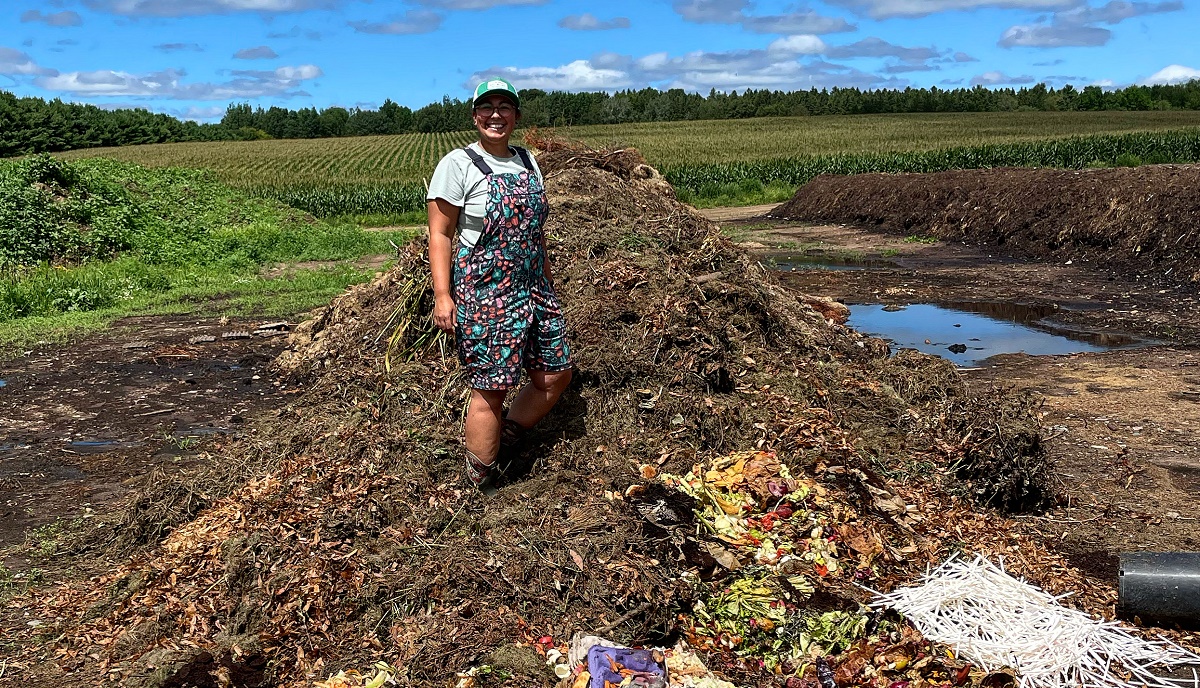 Photo of UW-Stevens Point student Maya Desai standing with compost created by residential and restaurant waste. She led a program that is reducing landfill waste in Wausau.