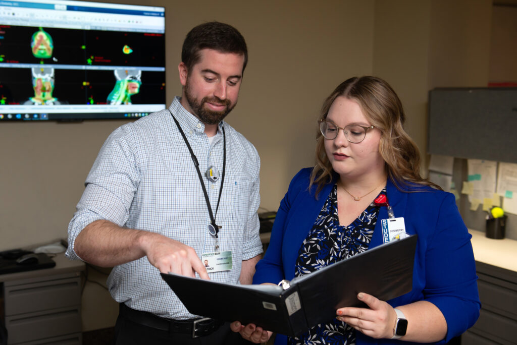 Photo of Medical Dosimetrist Patrick Melby who graduated from UWL with a degree in Nuclear Medicine Technology in 2012, applied for the medical dosimetry program in 2014 and was in the program 2015-2016. He now mentors UWL graduate student Paige Solie. “It is fun to watch a student — to watch the light bulb go on when they understand the concept,” he says. Photo courtesy of Gundersen Health System.