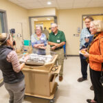 Photo of clinical instructor Allison Grady shows a baby manikin to guests touring the Ziemer Simulation Center. Looking on are Theresa Robinson (from left), Dave Robinson, Jos. Sauer and Kathryn Sauer. (UWM Photo/Troye Fox)