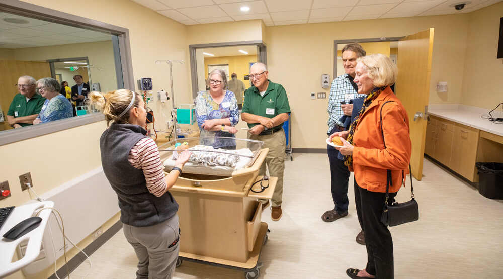 Photo of clinical instructor Allison Grady shows a baby manikin to guests touring the Ziemer Simulation Center. Looking on are Theresa Robinson (from left), Dave Robinson, Jos. Sauer and Kathryn Sauer. (UWM Photo/Troye Fox)
