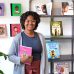 Photo of Ashley Valentine standing in Rooted MKE, her bookstore and tutoring center that focuses on the needs of Black, Indigenous and other people of color. “Books were kind of a haven for me. Now that I think about it, it’s sad. I was such an avid reader and had a love for reading, but I didn’t know there were books with characters who looked like me. I didn’t think people like me were capable of the things I was reading about.” (UWM Photo/Elora Hennessey)