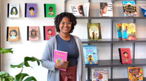 Photo of Ashley Valentine standing in Rooted MKE, her bookstore and tutoring center that focuses on the needs of Black, Indigenous and other people of color. “Books were kind of a haven for me. Now that I think about it, it’s sad. I was such an avid reader and had a love for reading, but I didn’t know there were books with characters who looked like me. I didn’t think people like me were capable of the things I was reading about.” (UWM Photo/Elora Hennessey)