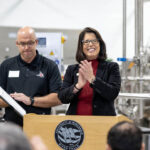 Photo of Chancellor Maria Gallo sharing applause with Trevor Wuethrich, Grassland Dairy Products, Inc. president, during a special gathering Thursday morning in the UWRF Dairy Pilot Plant.
