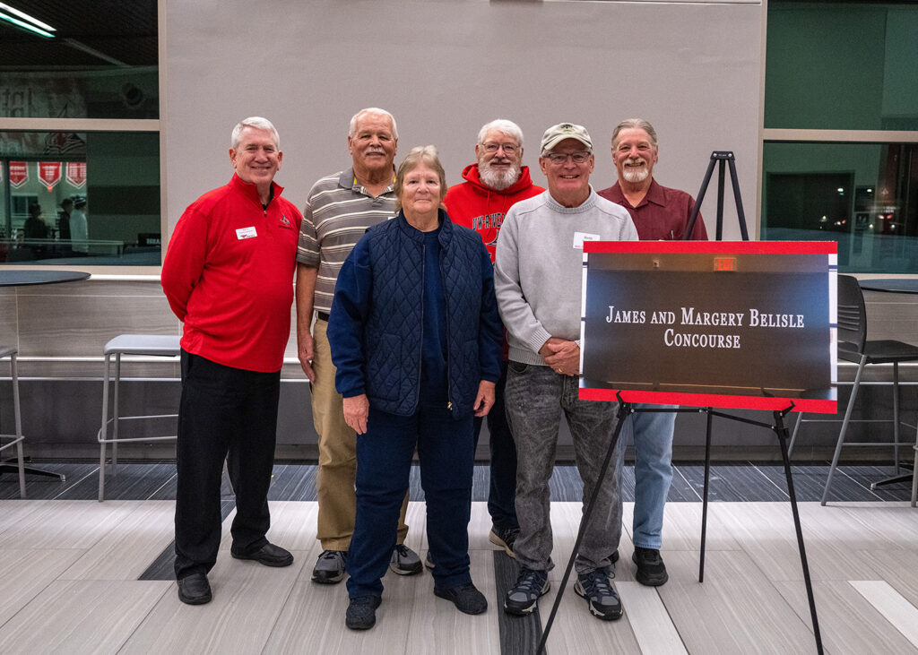 Photo of ceremony: The upper level of UWRF's Falcon Center, through which nearly all Falcon fans pass to attend home basketball and hockey games, will now be known as the James and Margery Belisle Concourse, following the 1954 graduates' $250,000 gift to the UW-River Falls Foundation. The couple wasn't able to attend the dedication ceremony but the Belisles' nephews and niece represented the family. From left: UWRF Assistant Chancellor for University Advancement Rick Foy and family members Craig, Jean, Lynn, Keith and Rich Geurkink.