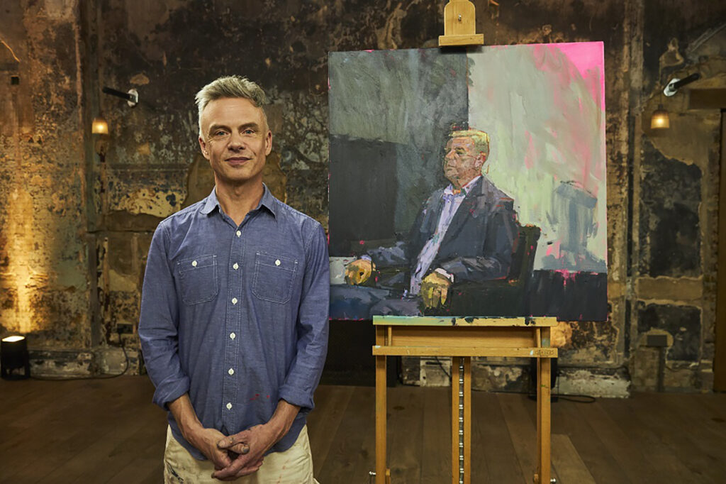 Photo of Tozer posing on the set of Portrait Artist of the Year with his painting of musician Suggs that won an opening round of the televised competition. (Photo courtesy of Tozer)