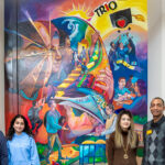Photo of some of the staff and students who contributed to the mural: Natalia Ornelas (from left), retention specialist/coach; Karen Parrish Baker, director of TRIO SSS; Maram Odeh Badad, junior IT major, SSS scholar and peer success assistant; Andreea Vasi, economics doctoral candidate and SSS program assistant; Demond Stewart, SSS senior advisor/coach; and Tia Richardson, artist. (UWM Photo/Elora Hennessey)