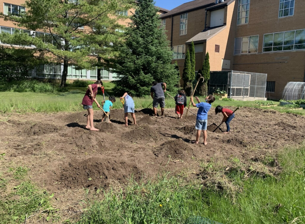 Photo of Dr. King’s students using gardening tools as they plant the Three Sisters garden. (Photo courtesy of Dr. King)