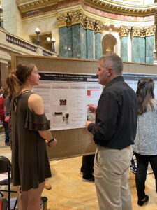 Photo of UW-River Falls student Cierra Kirkwood discussing her research about heavy metals in northern Wisconsin waterways with Rep. Shannon Zimmerman, R-River Falls, during the March 8 Research in the Rotunda event at the state Capitol in Madison. Beth Schommer/UWRF photo.