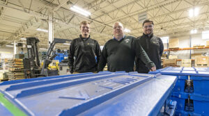 Photo of Easton Dobson (left) and Colin Haagensen flanking Steve Coolidge, general manager of AAA Sales & Engineering on the floor of the company’s Oak Creek plant. Dobson, Haagensen and another student, Ryan O’Day, worked on a project that benefited the company and gave the students real-world experience. (UWM Photo/Troye Fox)