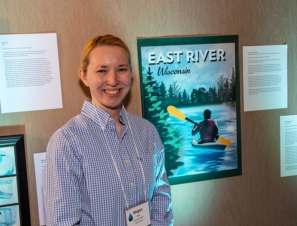 Photo of Megan Strom, graphic design major at UW-Stevens Point, posing with a travel poster she created for The Flow Project, which paired student artists and water professionals to create water-inspired art.