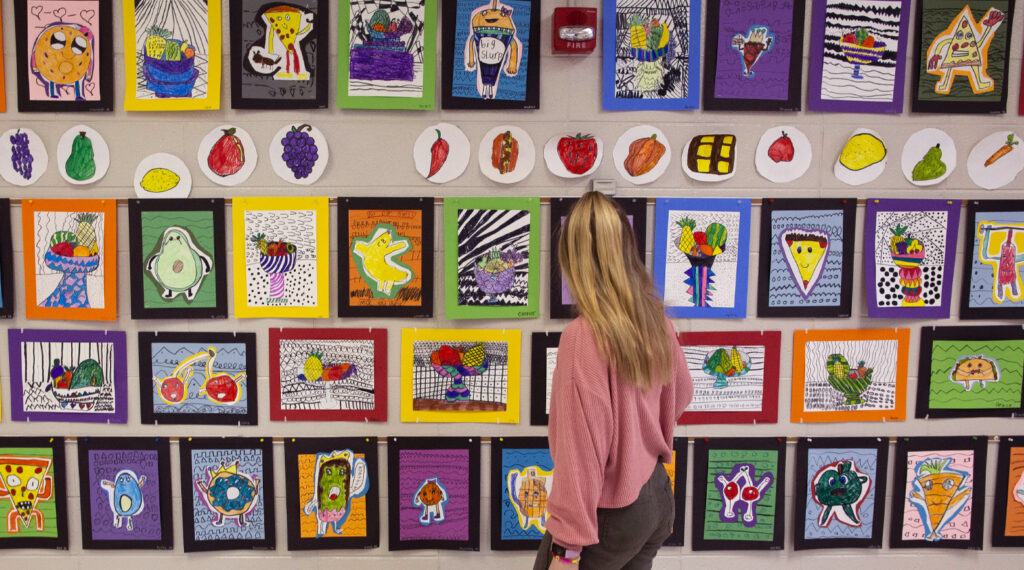 Photo of Hollyn Peterson, an art and art education major from Waukesha, looking at art she helped students create during her student teaching time at Meadowbrook Elementary School in Waukesha.