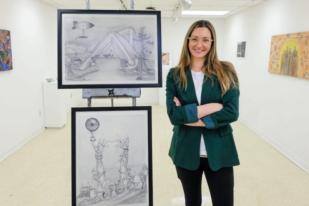 Photo of Kasie Lin Bazan, art major, posing with two pieces of her artwork inside Studio Arts' 407 Gallery. UW-Green Bay, Sue Pischke University Photographer