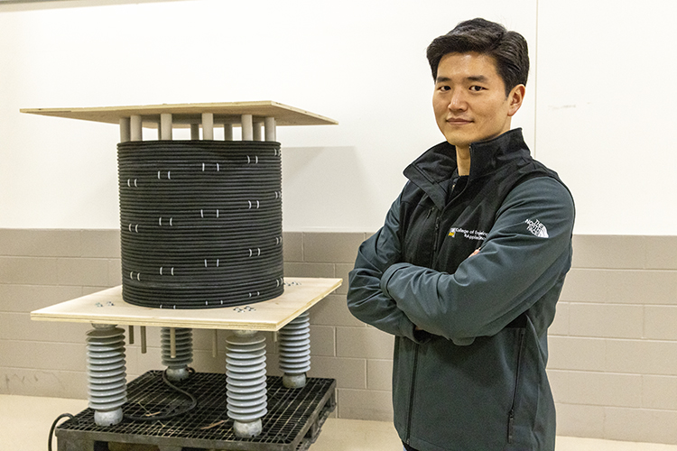 Photo of Chanyeop Park showing the inductor in his lab. It’s part of a research project he and Georgia Tech are working on to create a high-voltage circuit breaker that uses a much greener alternative to the gas currently used in high voltage electrical equipment. (UWM Photo/Troye Fox)