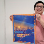 Photo of Jackson Yang with his favorite artwork from his master's thesis, 'A Thread through History,' displayed at the University Library Art Lab.