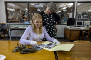 Photo of Penelope Hardy, associate professor of history, conducting research on oceanic history globally. This summer she works with Visiting Scholar Gillian to create a collection of primary sources on freshwater waterways. Pictures, in addition to books, have helped the two researchers think of all of the different ways people have relationships with water from ice fishing to baptisms.