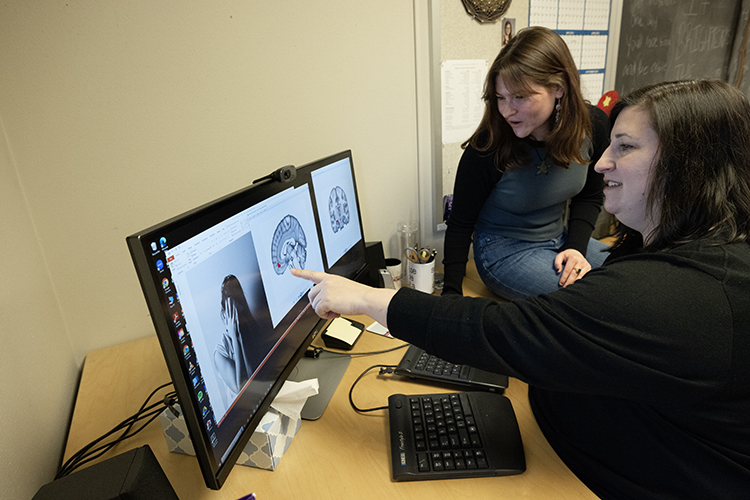 Photo of Psychology Professor Christine Larson and undergrad Alexandra Lato examining a brain scan on the computer. Telltale signs of trauma can be seen in brain scans of people who have visited the emergency department. "We've probably scanned over 1,000 people at MCW over the years," Larson said. "It still feels like a privilege to see what's happening inside people’s brains." (UWM Photo/Elora Hennessey)