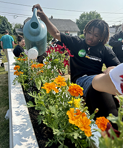 Photo of MPS student Damari Spears watering flowers at the grand opening. (UWM Photo/Oliver Johnson)