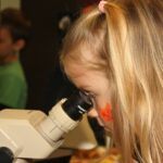 Photo of child looking through a microscope. Museum and planetarium shows for children are part of the free Junior Scientist program at UW-Stevens Point this fall.
