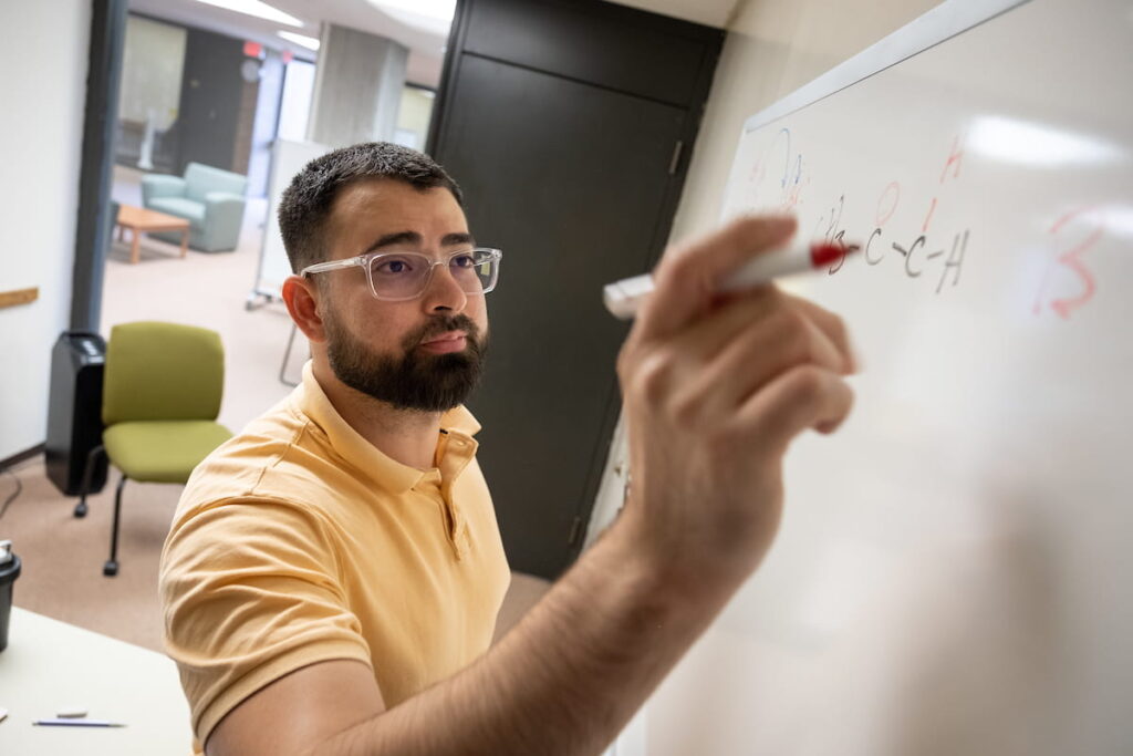 Photo of UW-Green Bay Human Biology major Adan Cordova working out chemistry formulas. Photos by Dan Moore, University Photographer