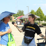 Photo of Jessie Thompson (right) talking with a shopper as part of the Story Cart Project this summer. UW-Milwaukee graduate students traveled with a mobile "story cart" to 27 Milwaukee locations to question strangers about food to collect stories about how people connect through food. (Photo courtesy of the Center for 21st Century Studies)