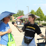 Photo of Jessie Thompson (right) talking with a shopper as part of the Story Cart Project this summer. UW-Milwaukee graduate students traveled with a mobile "story cart" to 27 Milwaukee locations to question strangers about food to collect stories about how people connect through food. (Photo courtesy of the Center for 21st Century Studies)