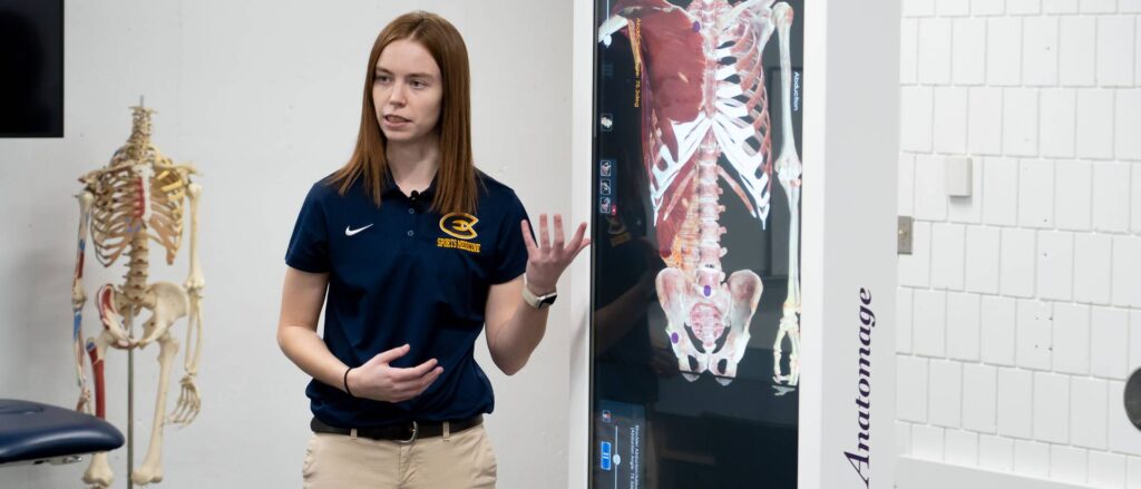 Photo of Hannah Geisler, an ad hoc program specialist in kinesiology, using the Anatomage table to instruct Blugolds in an anatomy class.