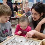 Photo of graduate students from Professor Barrett Klein's biology lab sharing a lesson on insects with children from Red Balloon Early Learning Center in La Crosse.