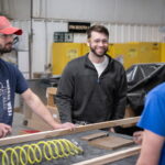 Photo of UW-Green Bay alumnus Michael Becker speaking with co-workers at the Central Wisconsin Woodworking Corporation in Wausau, Wisconsin. Photos by Dan Moore, University Photographer