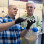 Photo of Scientists Steve Karlen and Vitaliy Tymokhin look over a reactor they used for their research on converting biomass into paracetamol.