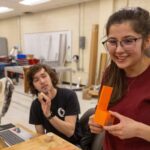 Photo of Mechanical engineering students Deric McConnell and Grace Goodreid demonstrate a 3D printed prototype for their toy assembly system project in the Senior Design Experience course. / UW-Stout