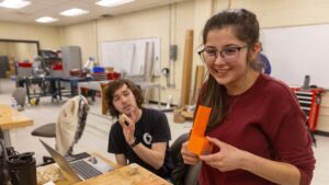 Photo of Mechanical engineering students Deric McConnell and Grace Goodreid demonstrate a 3D printed prototype for their toy assembly system project in the Senior Design Experience course. / UW-Stout