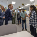 Photo of Brad Smith, vice chair and president of Microsoft, talking with Soumya Katukam (right) and Deepak Tandra, both information technology management graduate students at UW-Milwaukee (UWM), during a tour of the Connected Systems Institute at UWM. At left is UWM Chancellor Mark Mone. (UWM Photo/Troye Fox)