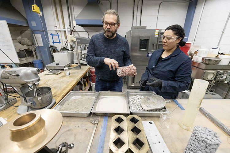 Photo of Konstantin Sobolev, UWM professor of civil engineering, and doctoral student Meraly Lopez Morales looking over concrete samples made with various added materials. A new NSF-funded research center in the College of Engineering & Applied Science will research high-performance concrete and greener methods of making concrete so that industry can bring discoveries into use. (UWM Photo/Troye Fox)